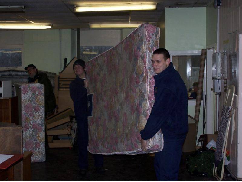 Volunteers carrying a mattress through the warehouse